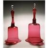 Image 1 : Two cranberry models of hand bells, each with a hollow handle and clear finial, 28cm & 29cm high,...