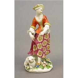 A Bow figure of a shepherdess, modelled standing contraposto, a recumbent lamb at her feet, paint...