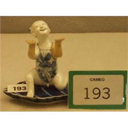 Unusual antique oriental kneeling figure on leaf shaped base in blue and white, bears signature,...