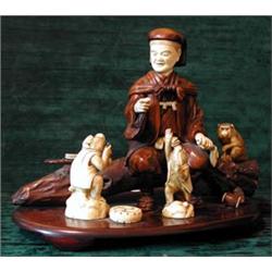 A Japanese carved ivory and hardwood figure group depicting a man seated on a...