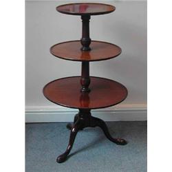 A George III mahogany dumb waiter with three circular tiers on turned column...