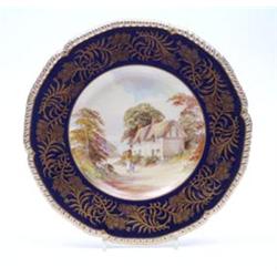 A Royal Crown Derby cabinet plate painted with a rural view by W.E.J. Dean, against a gilded blue...