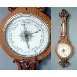 A Victorian oak wheel barometer with printed ceramic barometer dial and silvered thermometer dial...