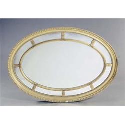 A gilt oval wall mirror with gadrooned, beaded and reed and tie bands, the central plate with a m...