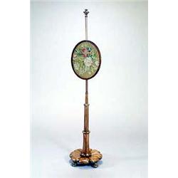 A William IV rosewood pole screen, with a leaf carved finial, an oval woolwork banner on reeded c...