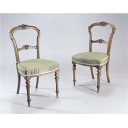 A set of six late Victorian walnut dining chairs, each with a carved back, a padded serpentine se...