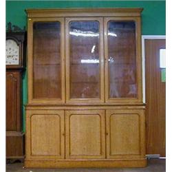 A Victorian honey oak library bookcase on cabinet the moulded cornice above a triple bookcase enc...