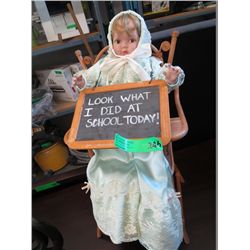 Doll in a wicker high chair with school slate