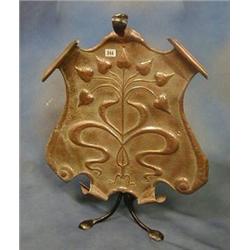 An Art Nouveau embossed copper and wrought iron fire screen of shield shape embossed flower heads...