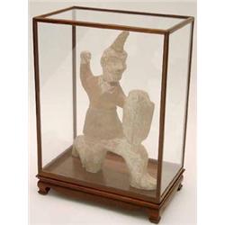 A painted grey pottery figure of a foreign warrior, kneeling on one leg and holding a shield in o...