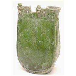 A green glazed flask, modelled in the form of leather bottle, the swelling body surmounted by fig...