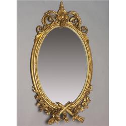 19th Century oval wall mirror within a gilt gesso frame decorated with bell husks, the floral des...