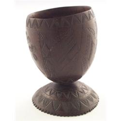 19th Century carved coconut cup with decoration of flags, thistle and shamrock, standing on a dom...
