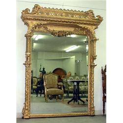 Large ornately framed over mantel mirror. Frame is adorned with pierce-carved scrolls, florals,...