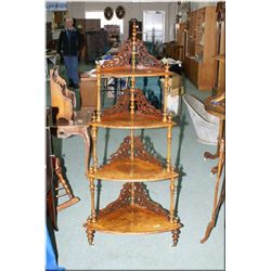 A four tier Victorian burl walnut étagère with fretwork backs and porcelain castors