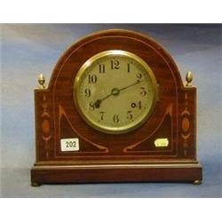 An Edwardian 8 day striking mantel clock contained in an arched shaped inlaid mahogany case, the...