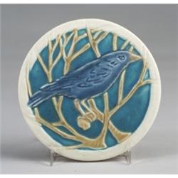 ROOKWOOD circular trivet tile, 1922, embossed with a blue bird on brown branch, against a blue gr…