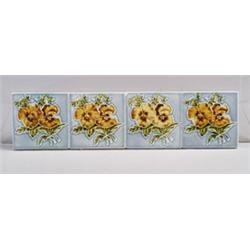 Twelve small European tiles, each embossed with two yellow and brown pansies on blue ground. A co…