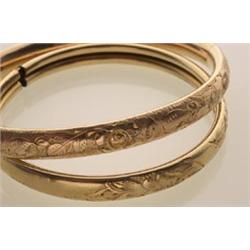 two vintage gold bangle bracelets Both in 14K yellow gold with chased and engraved foliate design...