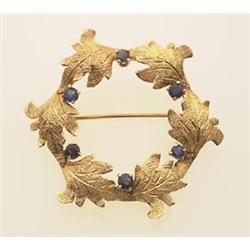 gold and sapphire brooch In 14K yellow gold, the brooch is designed as a wreath of six textured a...