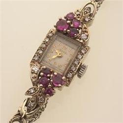 lady's wristwatch in diamonds, rubies and gold The bracelet and rectangular outer case is in 14K...