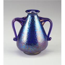 Vase of iridescent purple and blue glass with applied curvilinear handles. Unmarked. 7" x 6 1/2"....