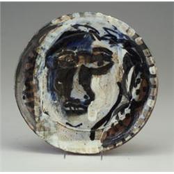 PETER VOULKOS stoneware charger with stylized face in blue, black, brown and white. Half-inch chi...