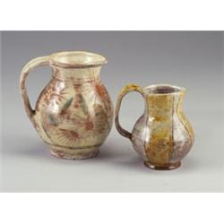 Two HENRY VARNUM POOR glazed redware pitchers: one with daisy motif and green leaves under a shee...