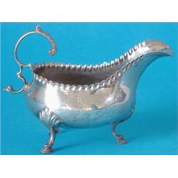 A George III silver sauceboat with crimped rim and leaf capped upscrolled handle on 3 scroll legs...