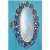 Image 1 : A gold dress ring claw set with a long oval moonstone within a border of 16 cushion shaped sapphi...