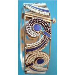 A gilt metal openwork hinged bangle, the scroll motifs with blue enamel and seed pearl decoration...