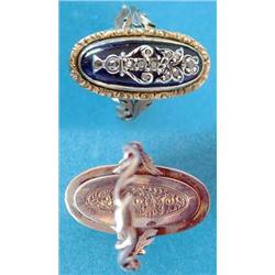 An early 19th century gold ring, the oval bezel inset with a blue glass plaque applied with a sil...