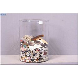 A large glass cylinder filled with vintage buttons and beads etc.