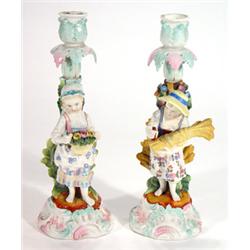 Pair of hand painted Continental porcelain candlesticks, one of a little girl with a basket of fl…