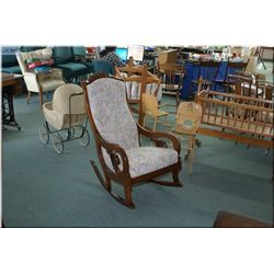 Antique Canadiana open armed rocker with carved back and upholstered seat and back