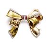 Image 1 : A GOLD, RUBY AND DIAMOND BOW BROOCH The two-toned gold bow enhanced with circular-cut diamond edg...
