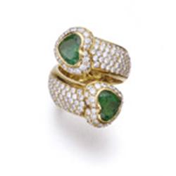 AN EMERALD AND DIAMOND RING Of crossover design, set with two heart-shaped emeralds weighing appr...