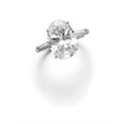 A DIAMOND RING The oval-shaped diamond weighing 5.71 carats to the tapered baguette-cut diamond s...