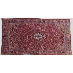 A KASHAN CARPET, 20th CENTURY, decorated on a red ground, 320cms x 480cms....