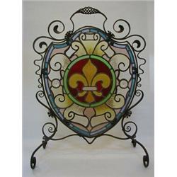 A HISTORICIST WROUGHT IRON FIRESCREEN, 19th Century, cartouche shape containing a stained glass p
