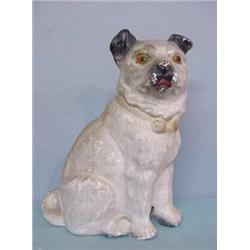 CHALK SEATED DOG. White with a short, curly tail and black painted ears and muzzle and yellow eye…