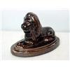 Image 1 : WHITE CLAY LION. Alert lion reclining on an oval base. Dark brown, shiny glaze. Incised initials.…