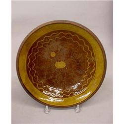 TWO PIECES OF REDWARE. Pie plate with golden brown slip decoration around the edges and a raised …