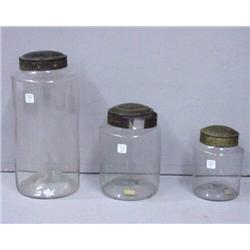 THREE BLOWN GLASS STORAGE JARS. The two smallest have tin lids. 6"h. 8"h. with broken blisters. 1…