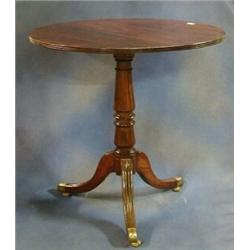 A Georgian mahogany snap top tea table with crossbanded top raised on a gun barrel column with pi...