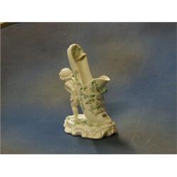 A Victorian Continental porcelain vase in the form of a slipper supported by a cherub 10" £40-60...