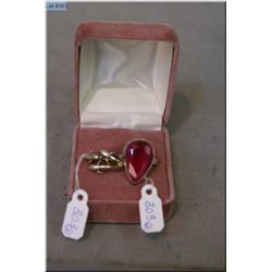 A sterling silver ring set with large pear shaped ruby gemstone and a sterling silver dolphin motif 