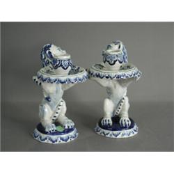 A pair of early 20th century Delft candlesticks modelled as heraldic lions seated upon their haun...