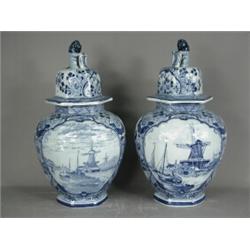 A pair of 1920's Delft vases and covers, with windmill scenes within cartouches, surmounted with...
