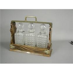 A late 19th century tantulus, the body with brass handles and a simulated coromandel frame with t...